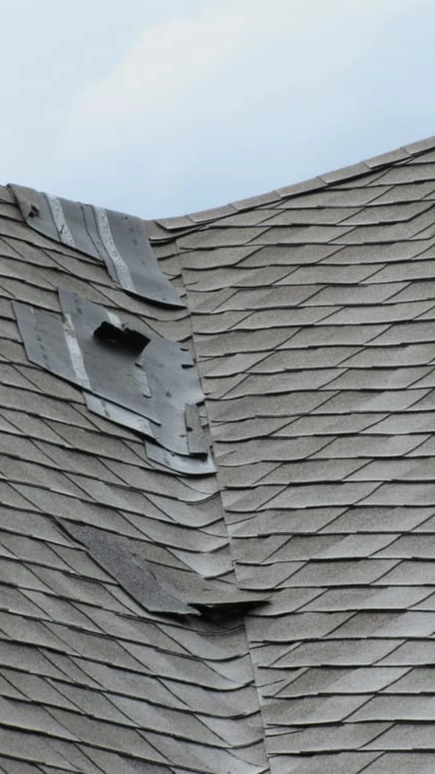 Camera viewfinder showing storm-damaged shingles with exposed underlayment